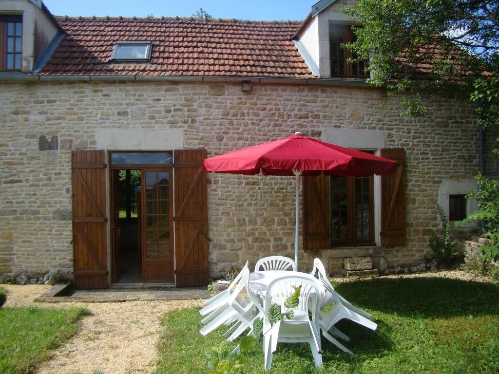 zwei weiße Stühle und ein Regenschirm vor einem Gebäude in der Unterkunft La maison d'Agnes en Haute Bourgogne in Jully