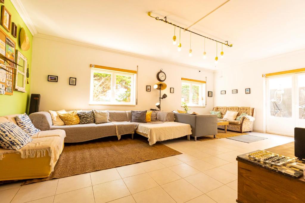 uma ampla sala de estar com um sofá e cadeiras em Pineapple Surf House em Peniche
