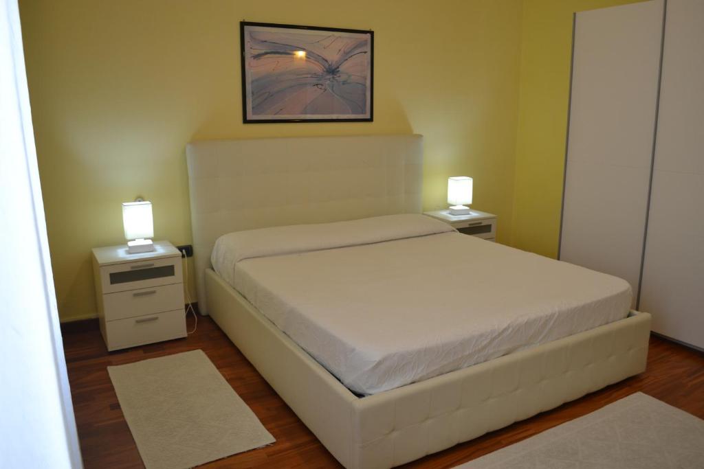 ein Schlafzimmer mit einem weißen Bett und zwei Nachttischen in der Unterkunft Apartments Via Spano - self check in in Alghero