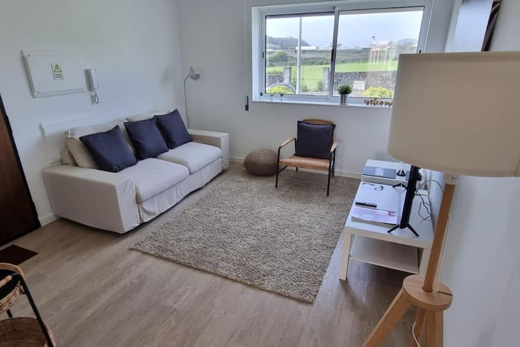 een woonkamer met een witte bank en een raam bij Apartamento Praia-Mar in Ponta Delgada