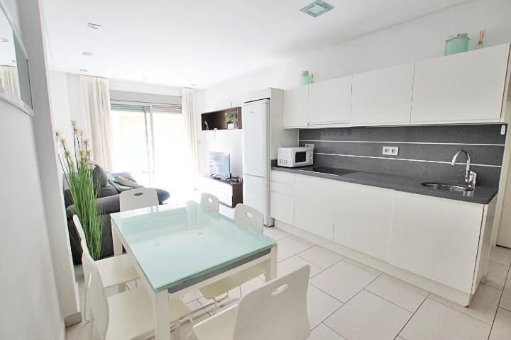 eine Küche mit weißen Schränken und einem Tisch im Zimmer in der Unterkunft Apartamento 10 Marjal Playa Centro de Guardamar in Guardamar del Segura