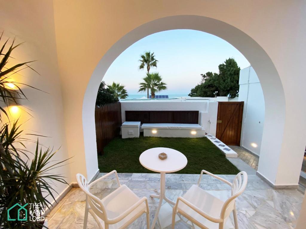 a patio with an archway and a table and chairs at New 1 bd with garden and sea side at Marsa Cornich in Douar el Hafey