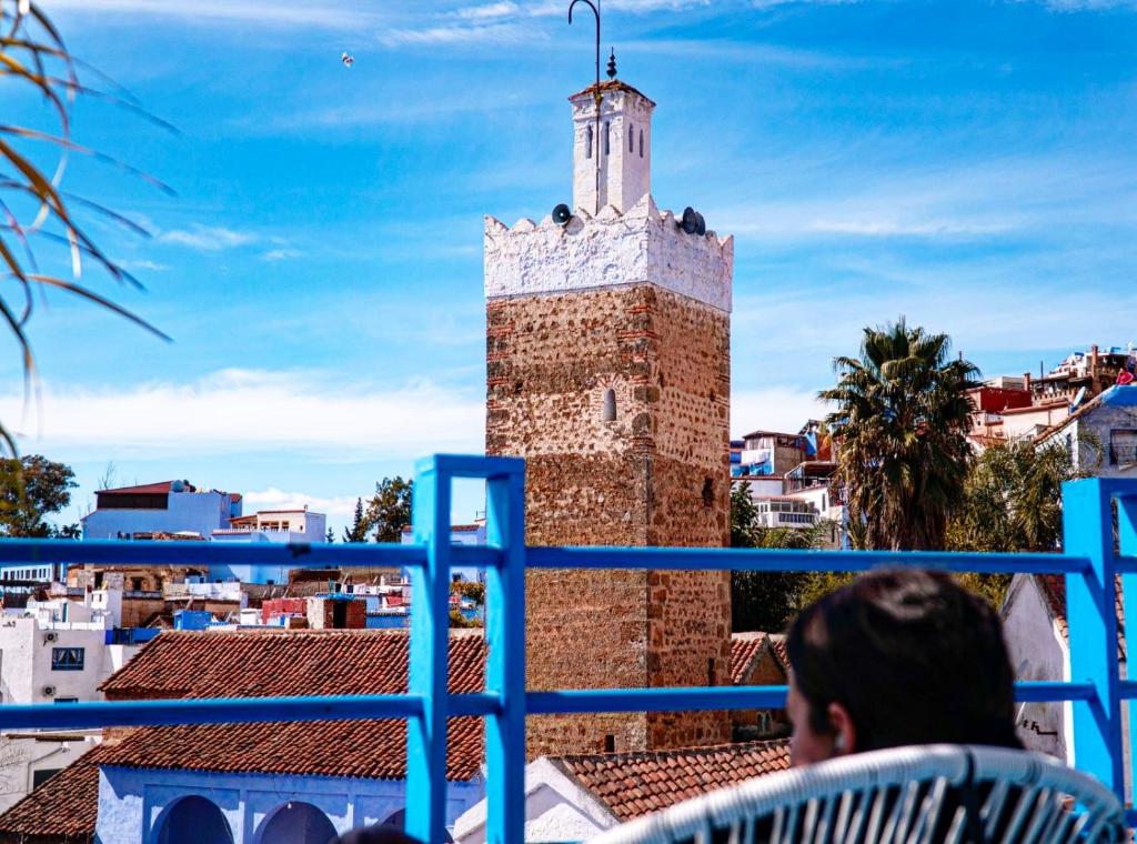 a man sitting on a balcony looking at a tower at USHA Guest House in Chefchaouen