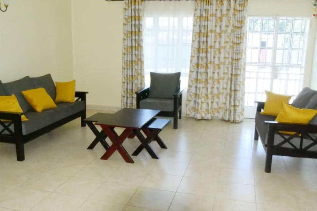 ein Wohnzimmer mit Sofas, einem Tisch und gelben Kissen in der Unterkunft Larry's Place - Gulu , Uganda in Gulu