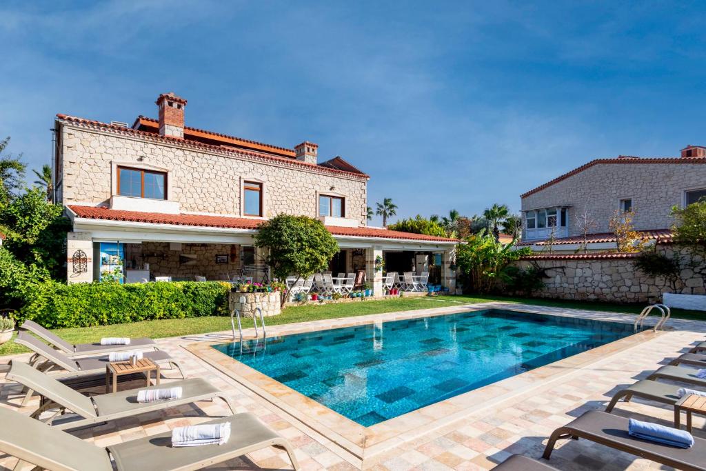 a house with a swimming pool and chairs at Alacati Koclu Konagi Hotel in Alaçatı