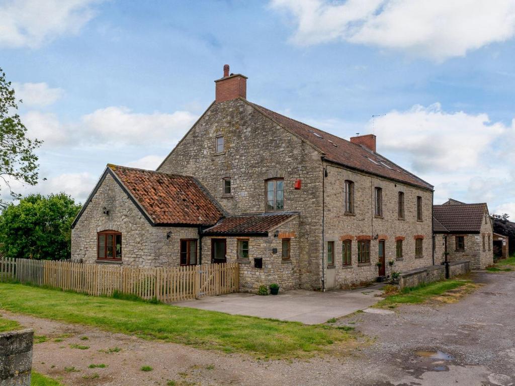 een oud stenen gebouw met een hek ervoor bij Mulberry Cottage in North Wootton