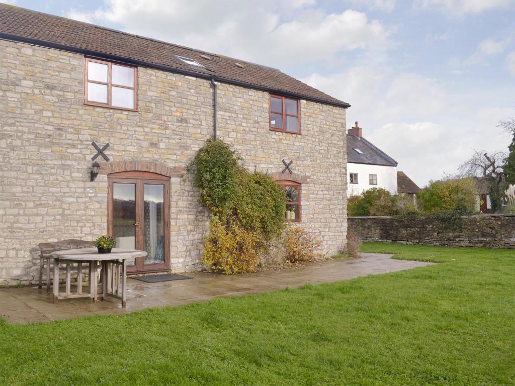 una casa de ladrillo con una mesa delante en The Creamery, en North Wootton