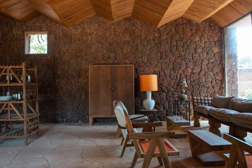 a living room with a couch and a stone wall at Maison Pierres in Toubab Dialaw
