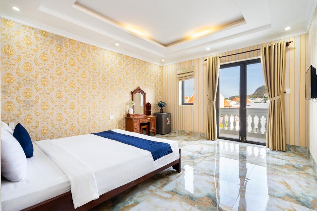 ein Schlafzimmer mit einem großen Bett und einem Balkon in der Unterkunft Joi Hospitality - KP House in Vũng Tàu