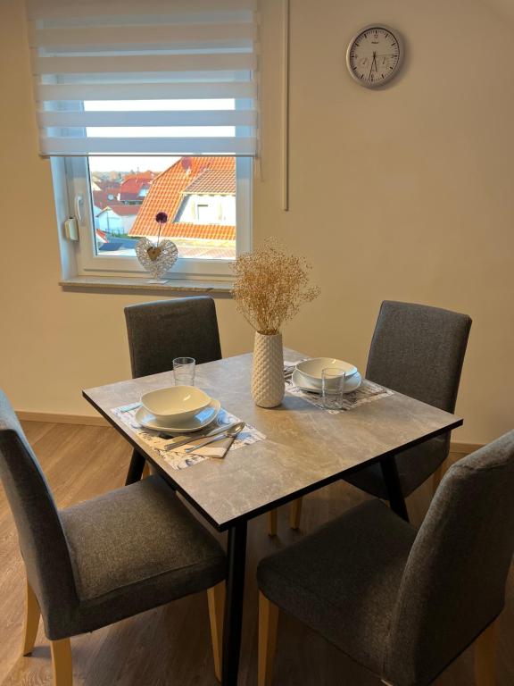 a dining room table with chairs and a clock on the wall at Ferienwohnung Löwen in Wabern