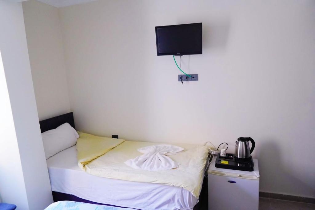 Habitación pequeña con cama y TV en la pared. en Hotel Resat, en Izmir