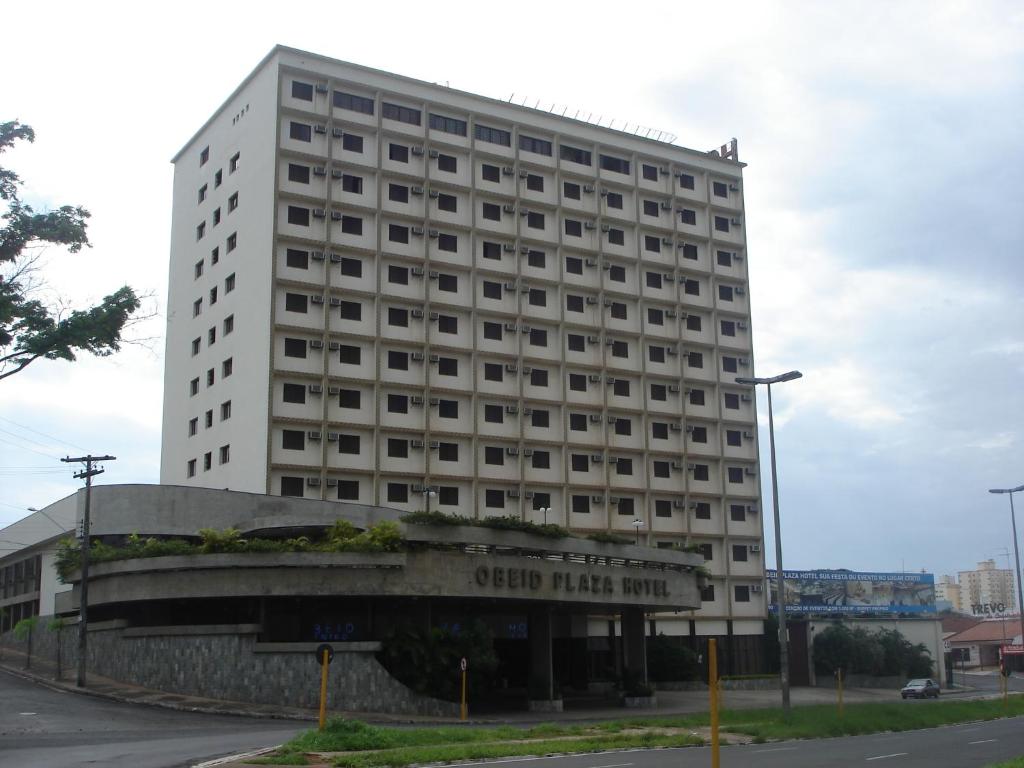 un edificio blanco alto con un cartel delante en Obeid Plaza Hotel, en Bauru