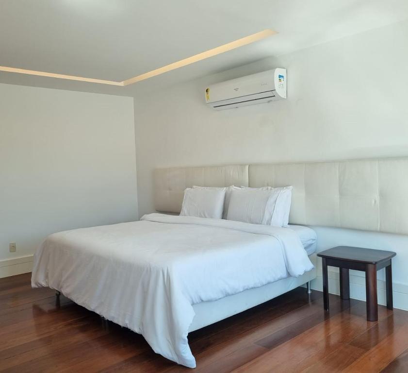 a bedroom with a white bed and a table at Cobertura COM PISCINA in Rio de Janeiro