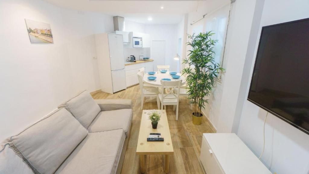 sala de estar con sofá blanco y mesa en RentalSevilla Disfruta por San Leandro en un alojamiento con 3 habitaciones en Sevilla