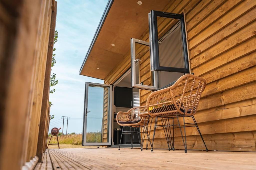 ein Paar Stühle auf der Veranda eines Hauses in der Unterkunft Lakeside Lodge- 'Swallow' in Bishampton