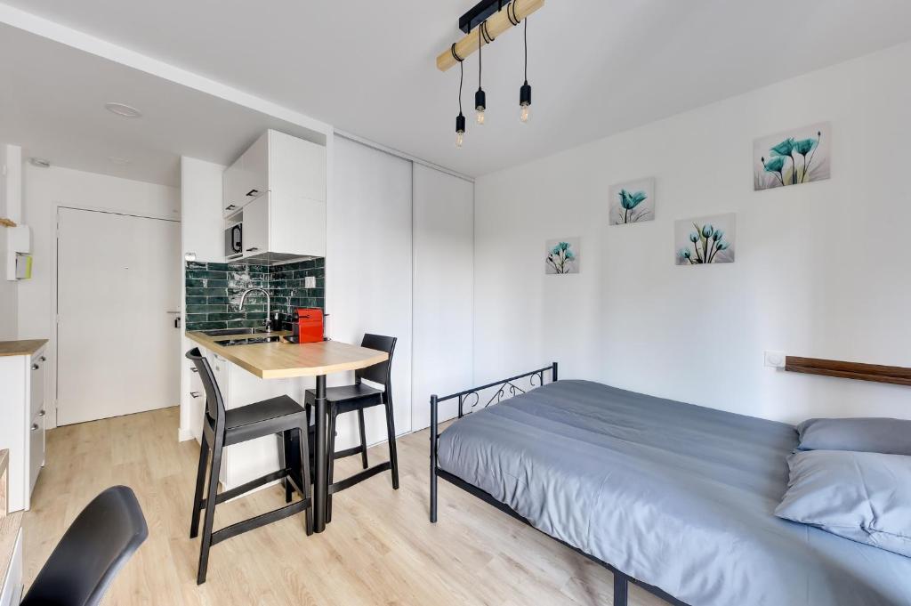 a bedroom with a bed and a table and chairs at Le Casual- Clichy in Clichy