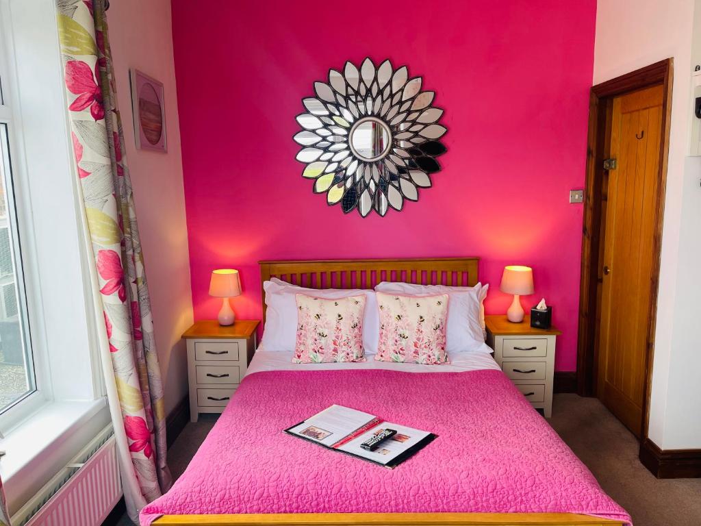 Dormitorio rosa con cama rosa y espejo en The Railway Inn en Rise