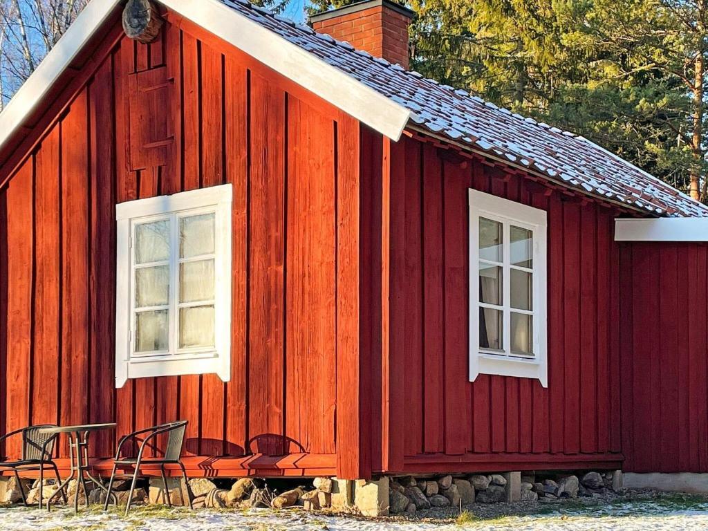 Malmköping的住宿－Holiday home ESKILSTUNA V，红色的房子,外面有两扇窗户和椅子