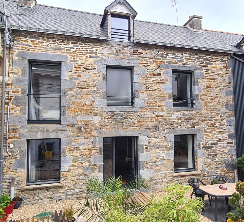 a stone house with black windows and a patio at Gîte de l'Aff in La Gacilly