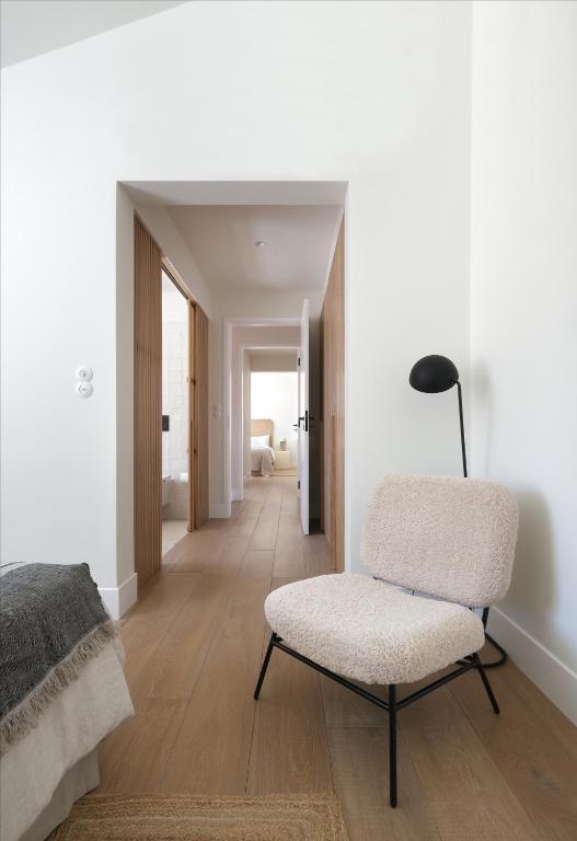 a white room with a chair and a bedroom at Villa Sofia Cascais in Cascais