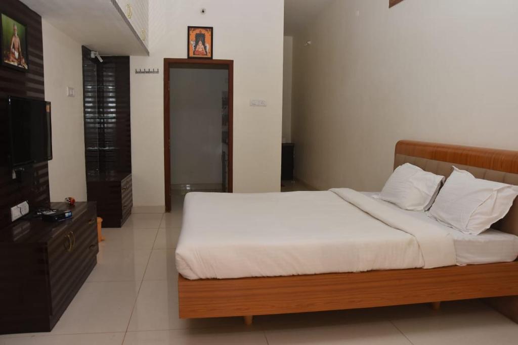 um quarto com uma cama e uma televisão de ecrã plano em arulmigu sivasakthi siddhar peedam garden guest house em Tiruvannamalai