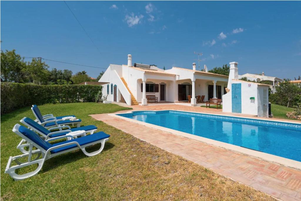 a pair of blue lounge chairs next to a swimming pool at Villa Alegria in Loulé