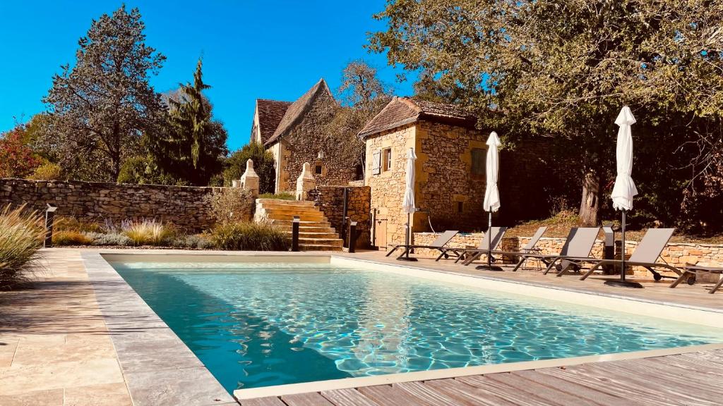 una piscina con sillas y una casa en La Combe d’Estève en Carsac-Aillac