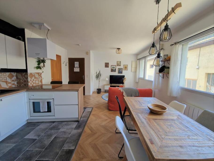 a kitchen and living room with a wooden table and a dining room at T2 refait à neuf avec parking à 1000m du lac in Annecy