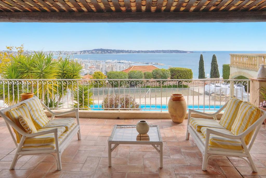 d'une terrasse avec deux chaises et une table offrant une vue. dans l'établissement IMMOGROOM- Top of villa 200m2 - Garden - Pool - Sea view - Parking - Wifi, à Vallauris