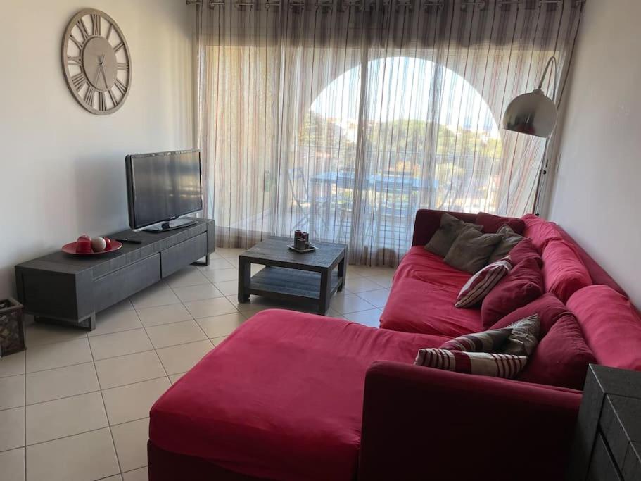 a living room with a red couch and a tv at Appartement T3 Les eucalyptus in LʼÎle-Rousse