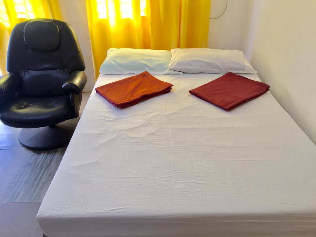 ein Bett mit zwei Handtüchern darauf mit einem Stuhl in der Unterkunft Harvey's Place in Cagayan de Oro
