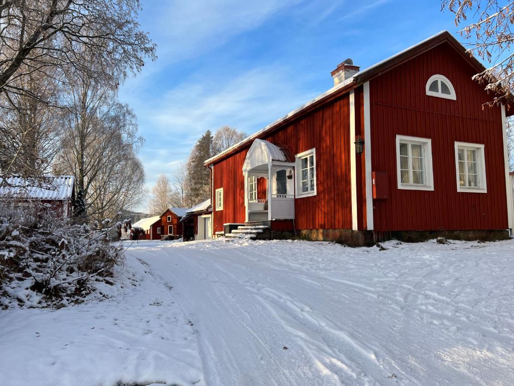 a red barn in the snow on a snowy road at High Noon Westernranch Holidayhouse in Ljusdal