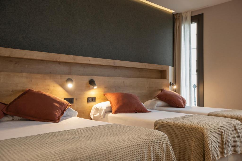 Habitación de hotel con 2 camas con almohadas de color naranja en Fontanella By BCN URBAN Rooms, en Barcelona