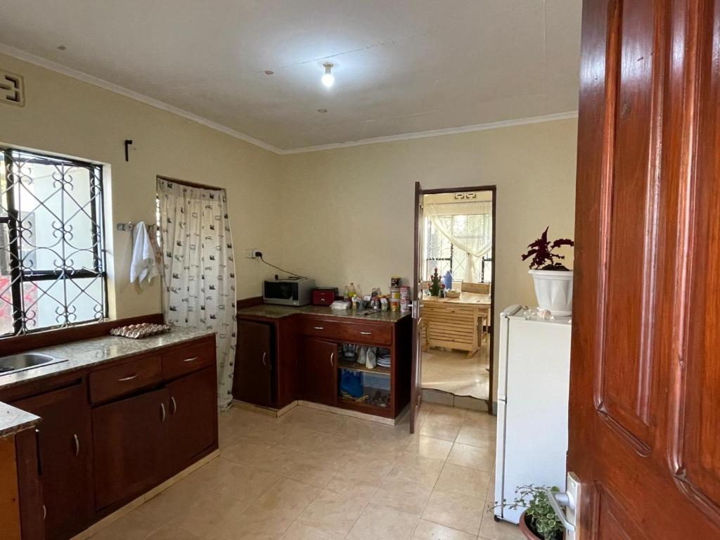 een keuken met houten kasten en een witte koelkast bij Wonders Hostel in Arusha