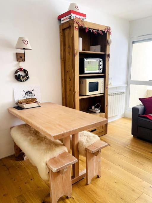 a wooden table in a living room with a microwave at Ski apartment 3 valleys in Les Menuires