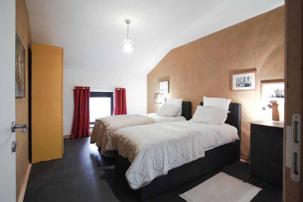 Sainte-CécileにあるLa Grange du Donatの赤いカーテン付きのベッド2台が備わるホテルルームです。