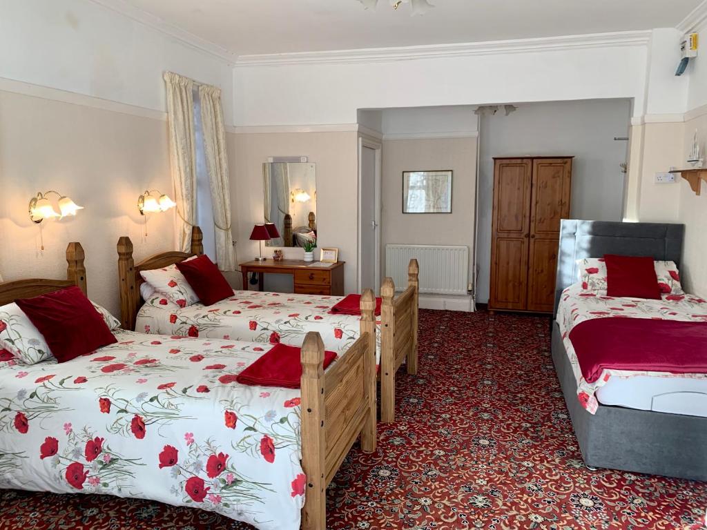 a bedroom with two beds with red and white sheets at Knighton Lodge in Skegness