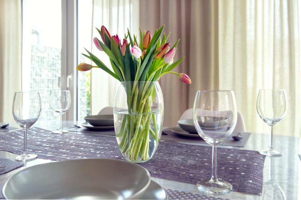 a table with a vase of flowers and wine glasses at Modern Wohnen I Smart TV I Terrasse I 2x Parkplatz I 2 Schlafzimmer I 6 Schlafplätze in Bad Oeynhausen