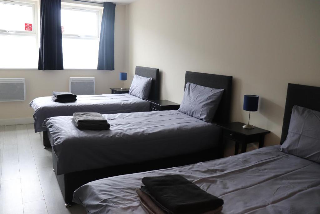 two beds in a room with two windows at Dockside Lodge in Liverpool