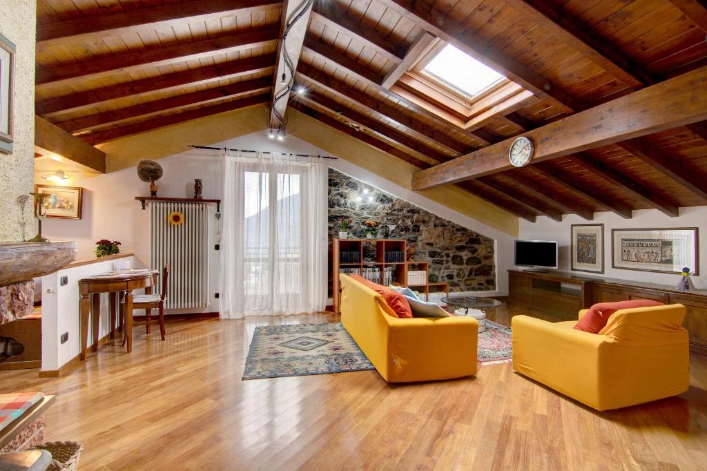 Sala de estar con 2 sillas amarillas y mesa en La Mansarda di Eros e Tiziana, en Lanzo d'Intelvi