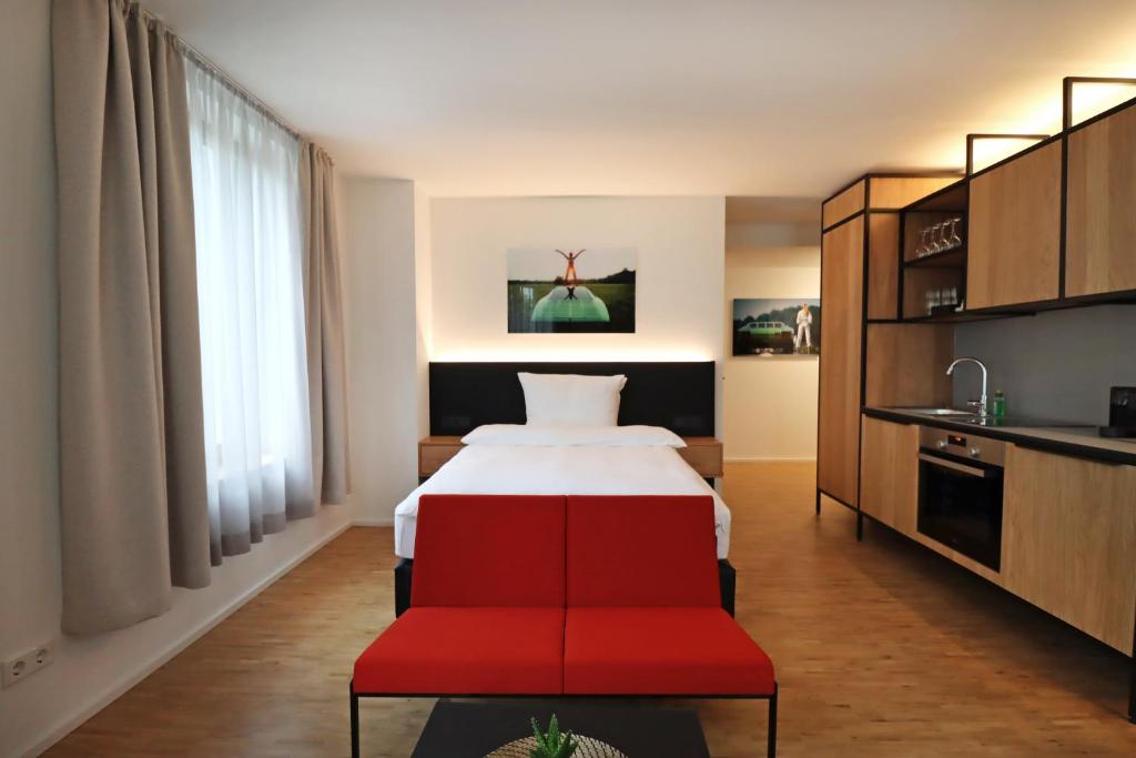 um quarto de hotel com uma cama e uma cadeira vermelha em S12 - Boardinghouse by Hotel Trezor em Singen