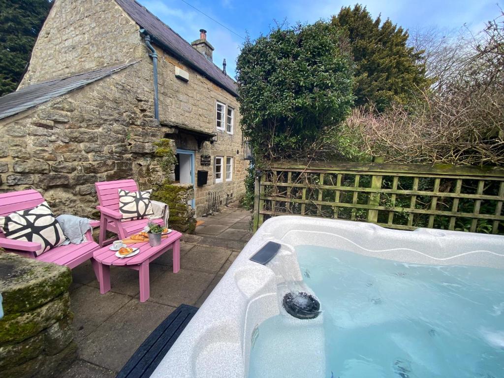 an outdoor hot tub in front of a cottage at Jacks Cottage, Curbar in Curbar