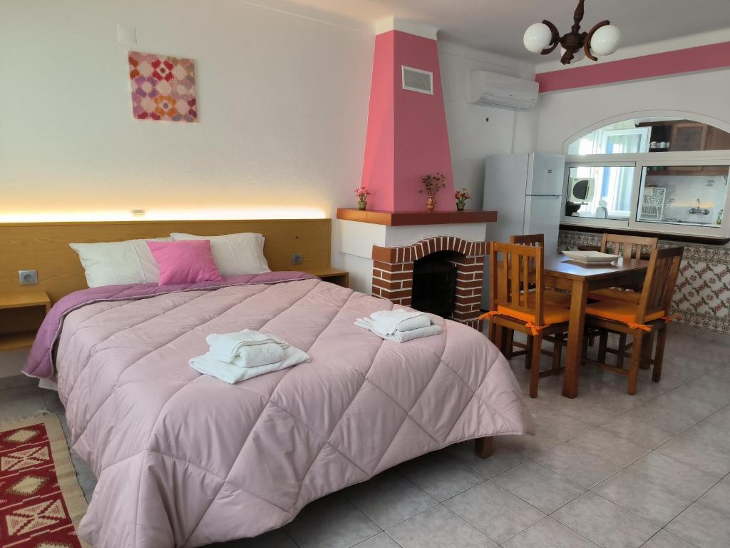 a bedroom with a bed and a table and a fireplace at Apartamentos Campos 0 in Porto Covo