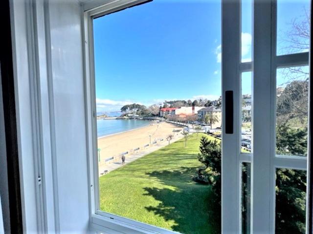 uma janela com vista para a praia e para o oceano em playa Santa Cristina em Oleiros