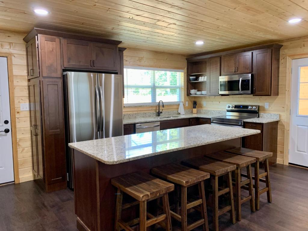 a kitchen with wooden cabinets and a large island with bar stools at The Brick House: Brand NEW! 3 Bedroom Home with private driveway in Pigeon Forge
