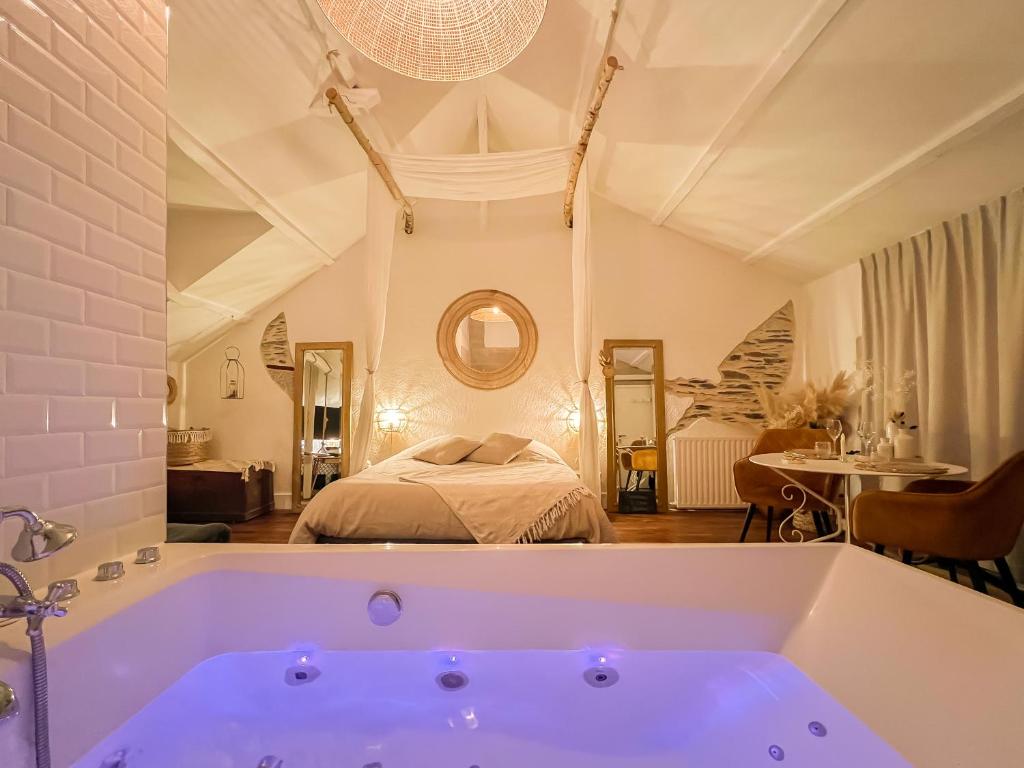 a bathroom with a large tub in front of a bedroom at Love Room Bohème Les Petits Plaisirs in Angers