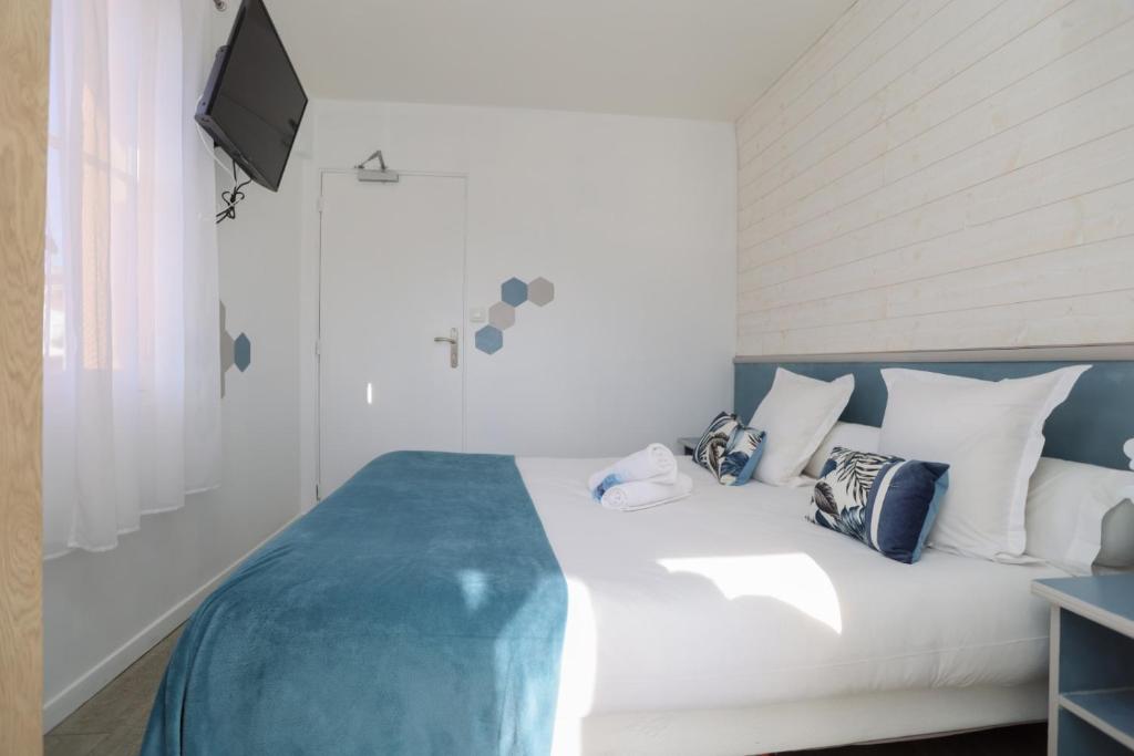 a bedroom with a white bed with blue and white pillows at Hostellerie LE PANEL in Mandelieu-La Napoule