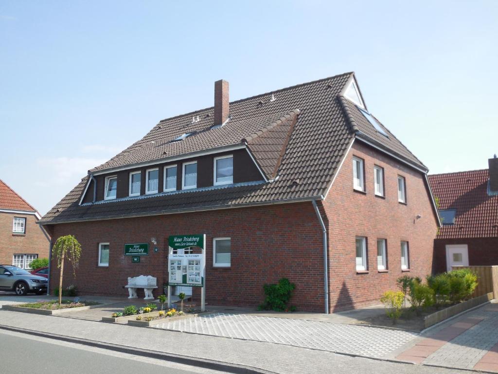 une grande maison en briques rouges avec un toit noir dans l'établissement Wohnung Typ A im Haus Friedeburg EG, Carolinensiel, à Carolinensiel