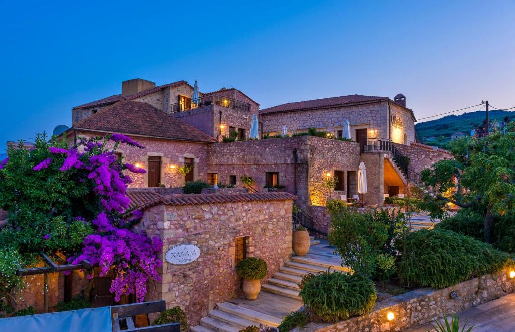 uma grande casa de pedra com flores roxas em frente em Spilia Village Hotel & Villas em Spiliá