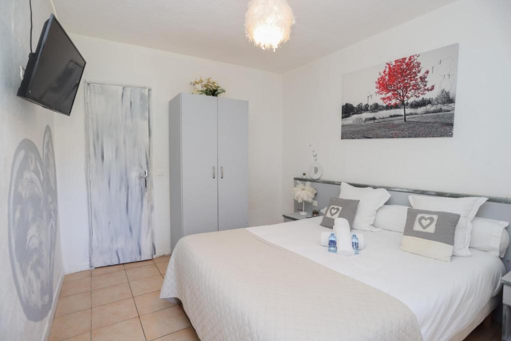 a bedroom with a large white bed and a tv at Hostellerie LE PANEL in Mandelieu-La Napoule